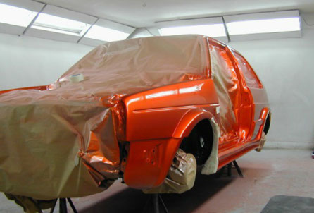 Orange car masked up in the spray booth